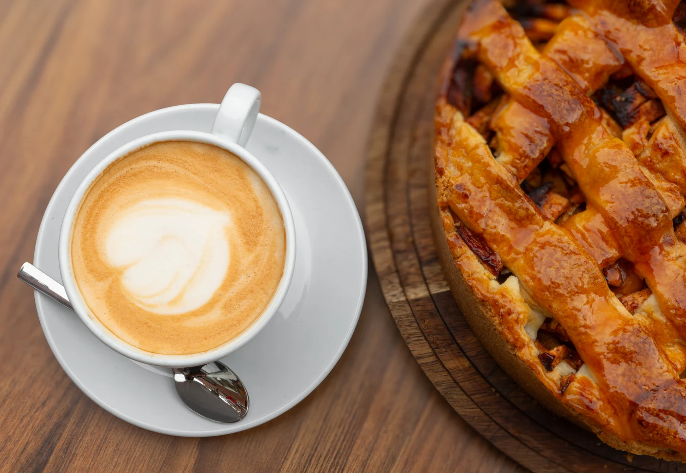 Een cappuccino naast een huisgemaakte appeltaart.